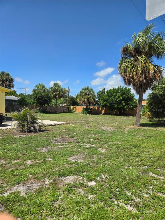 A grassy, vacant lot features several palm trees and a wooden fence in the background — 239 NE 18TH AVENUE, POMPANO BEACH, FL