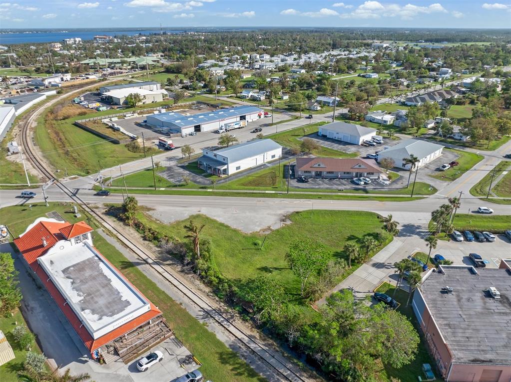 An aerial view shows commercial buildings, a railroad track, and surrounding residential areas — 1013 TAYLOR ROAD, PUNTA GORDA, FL