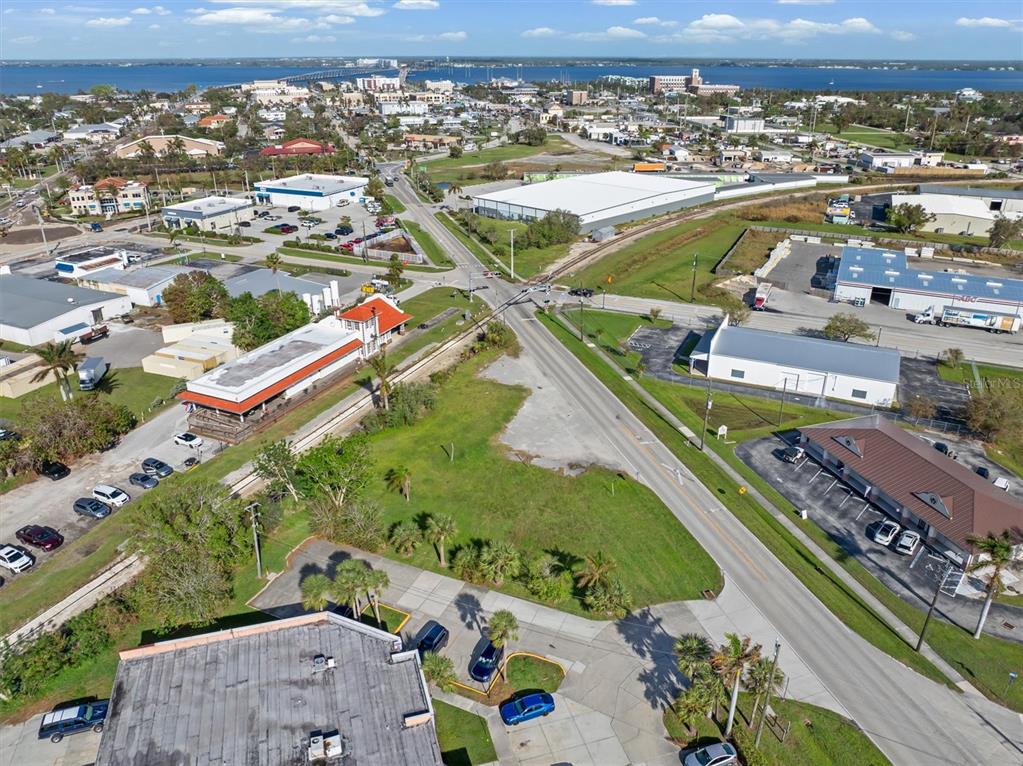 An aerial view shows a commercial area with buildings, parking lots, and a railroad track — 1013 TAYLOR ROAD, PUNTA GORDA, FL