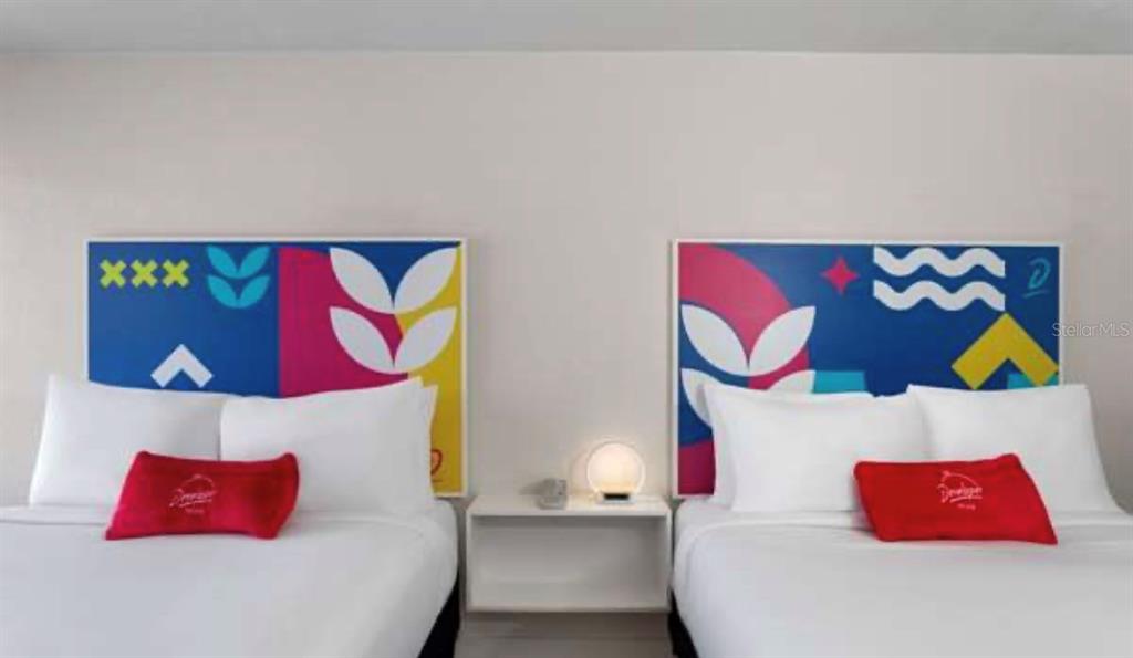 A hotel room features two beds with colorful abstract headboards and a central nightstand — 2930 POLYNESIAN ISLE BOULEVARD UNIT 223, KISSIMMEE, FL