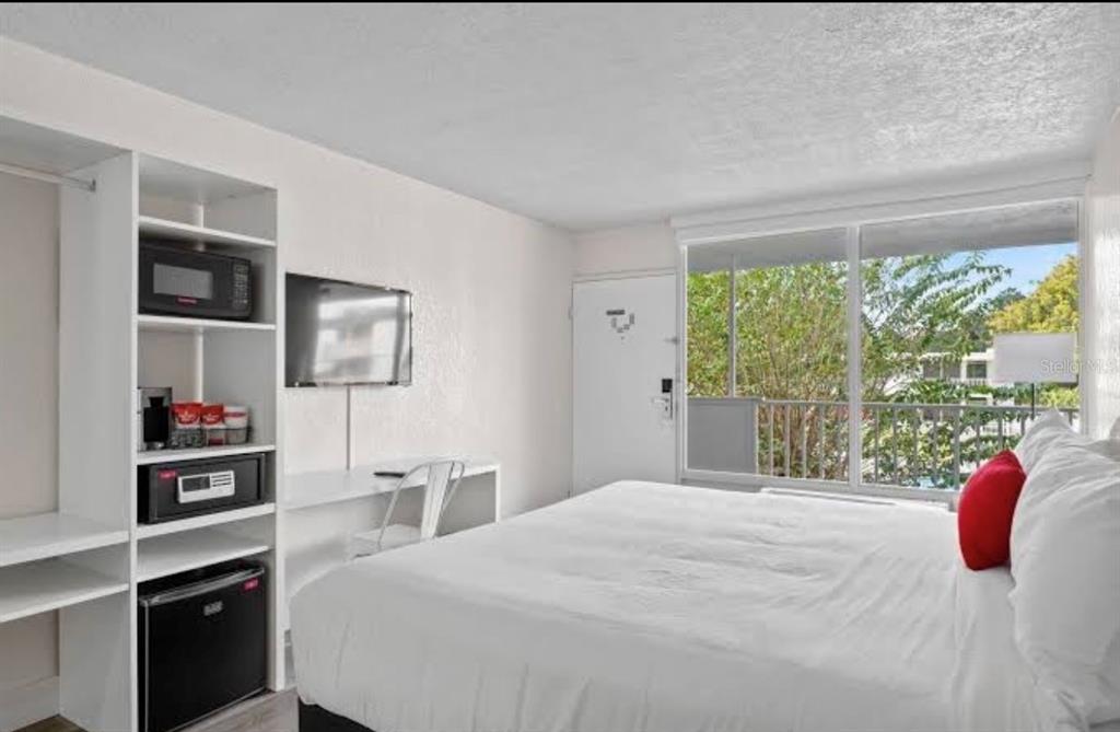 A hotel room features a bed, a desk, a wall-mounted television, and a kitchenette unit — 2930 POLYNESIAN ISLE BOULEVARD UNIT 223, KISSIMMEE, FL