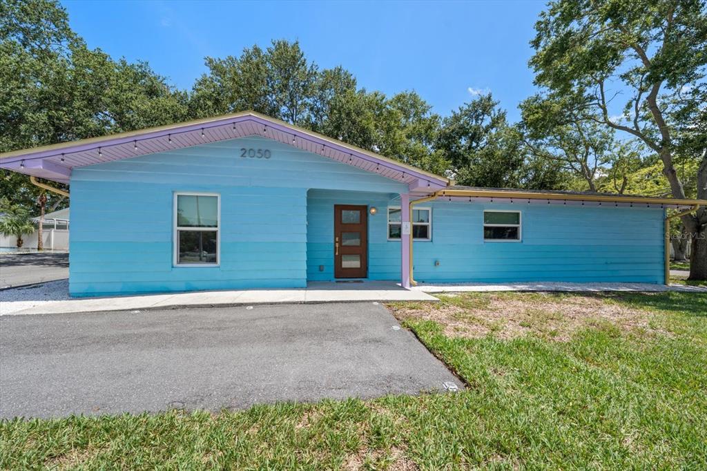 A backyard patio features a fire pit, colorful Adirondack chairs, string lights, and a grill — 2050 W BAY DRIVE, LARGO, FL