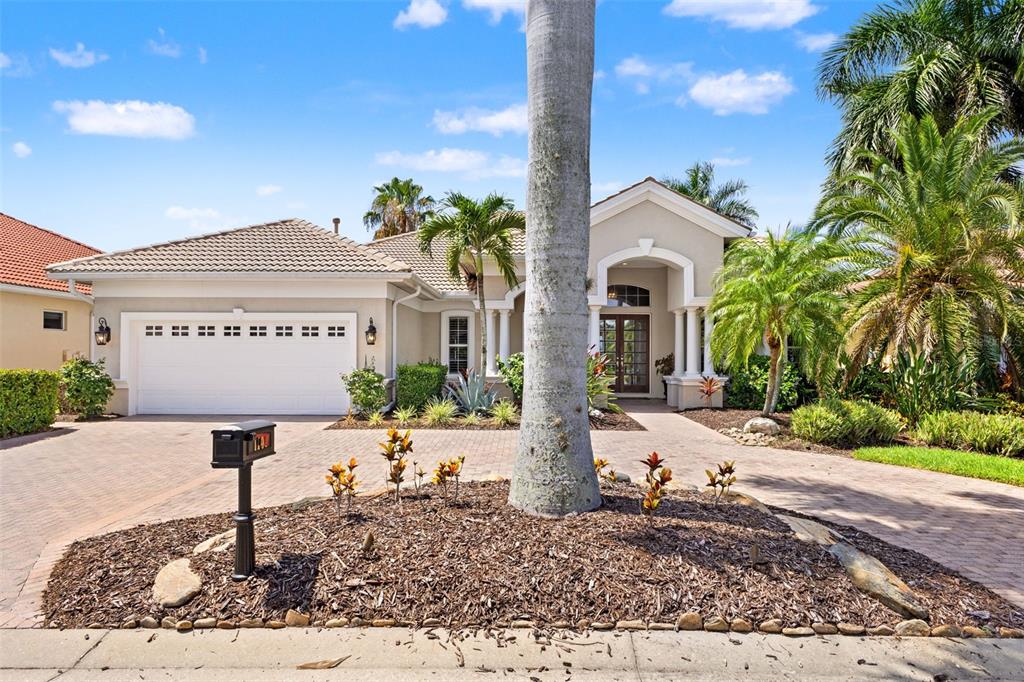 A single-story house with a white garage, paved driveway, and a palm tree in front — 1105 3RD STREET E, PALMETTO, FL
