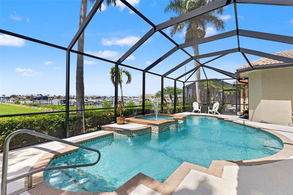 A screened-in pool and spa area overlooks a marina with boats under a blue sky — 1105 3RD STREET E, PALMETTO, FL