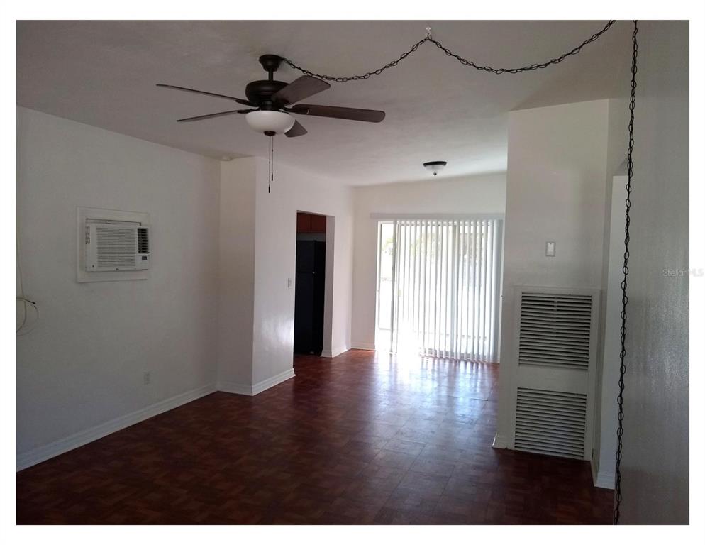 An interior view of a room with dark wood flooring, a ceiling fan, and sliding doors — 446 NEW YORK AVENUE, DUNEDIN, FL