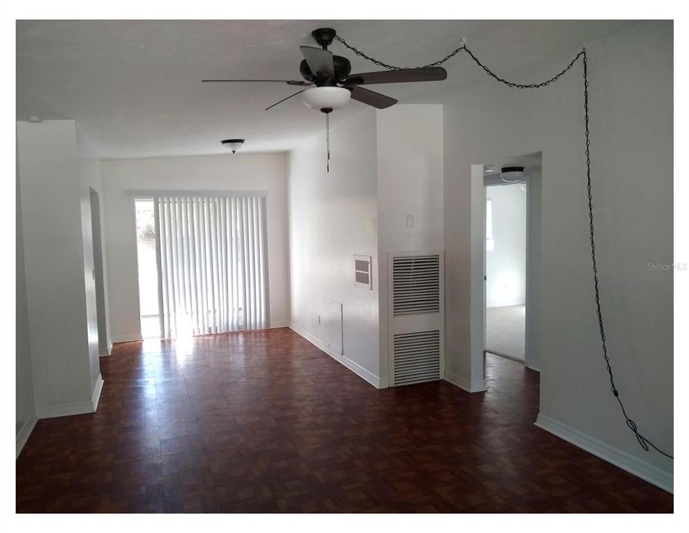 An interior room features dark parquet wood flooring, white walls, and a ceiling fan — 446 NEW YORK AVENUE, DUNEDIN, FL