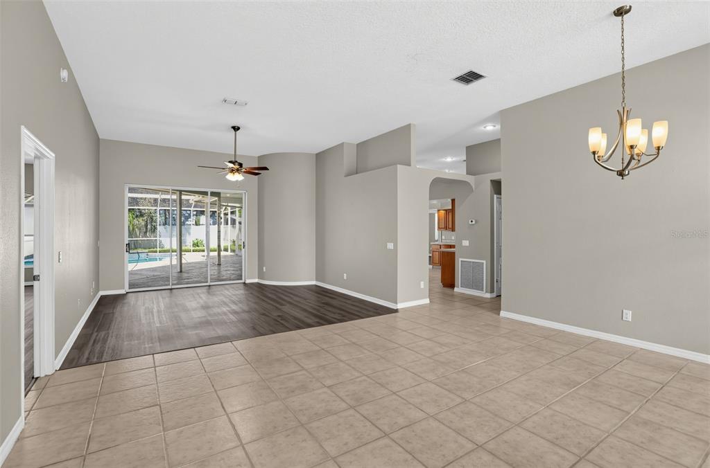 An open-concept living area features tile flooring, a dark wood-look section, and a sliding glass door — 248 HUNTRIDGE WAY, WINTER SPRINGS, FL