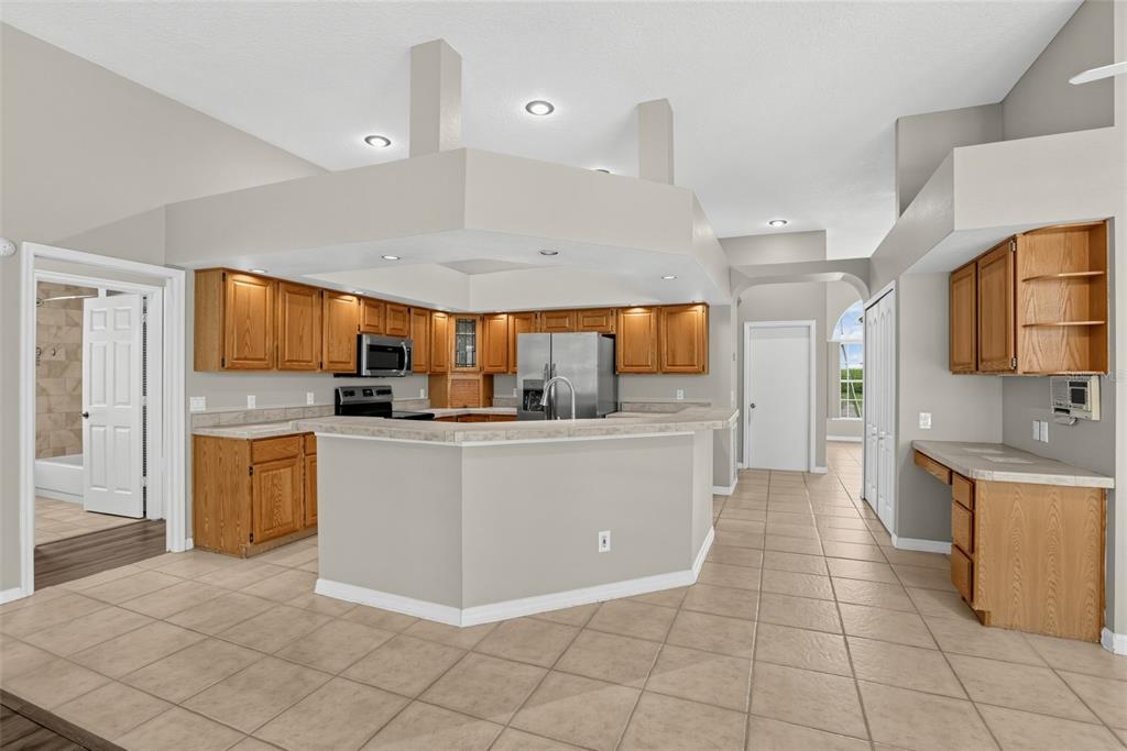 A kitchen with oak cabinets, a breakfast bar, and tile flooring under a vaulted ceiling — 248 HUNTRIDGE WAY, WINTER SPRINGS, FL