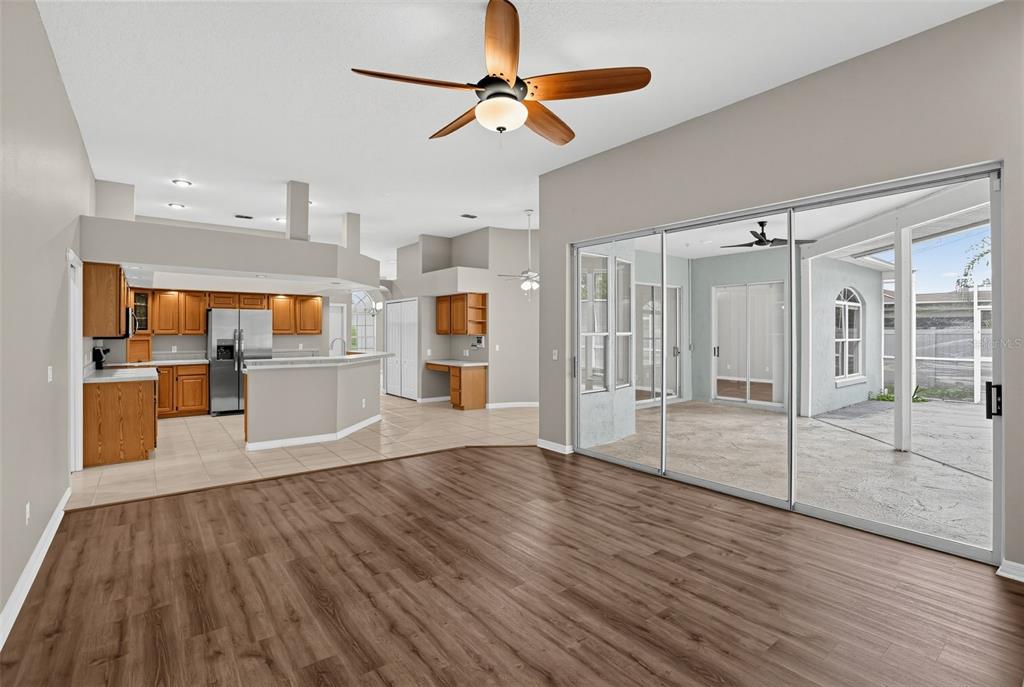 A living room with wood-look flooring opens to a kitchen and a covered outdoor patio — 248 HUNTRIDGE WAY, WINTER SPRINGS, FL