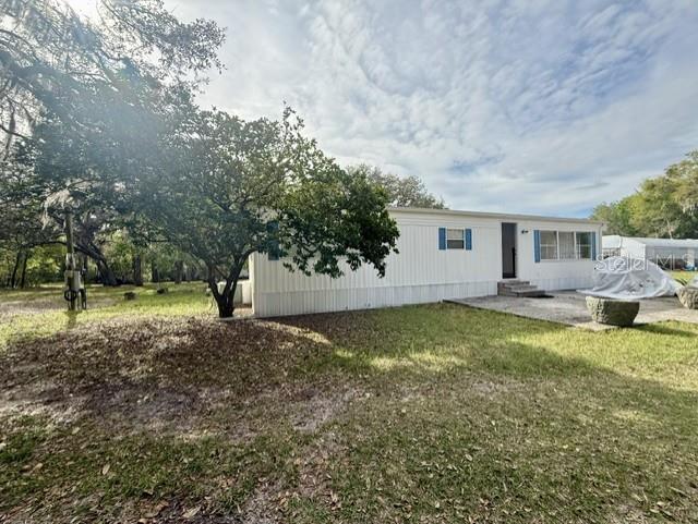 A white mobile home sits on a grassy lot with a large tree in front — 2424 JUNIOR AVE. Unit B, APOPKA, FL