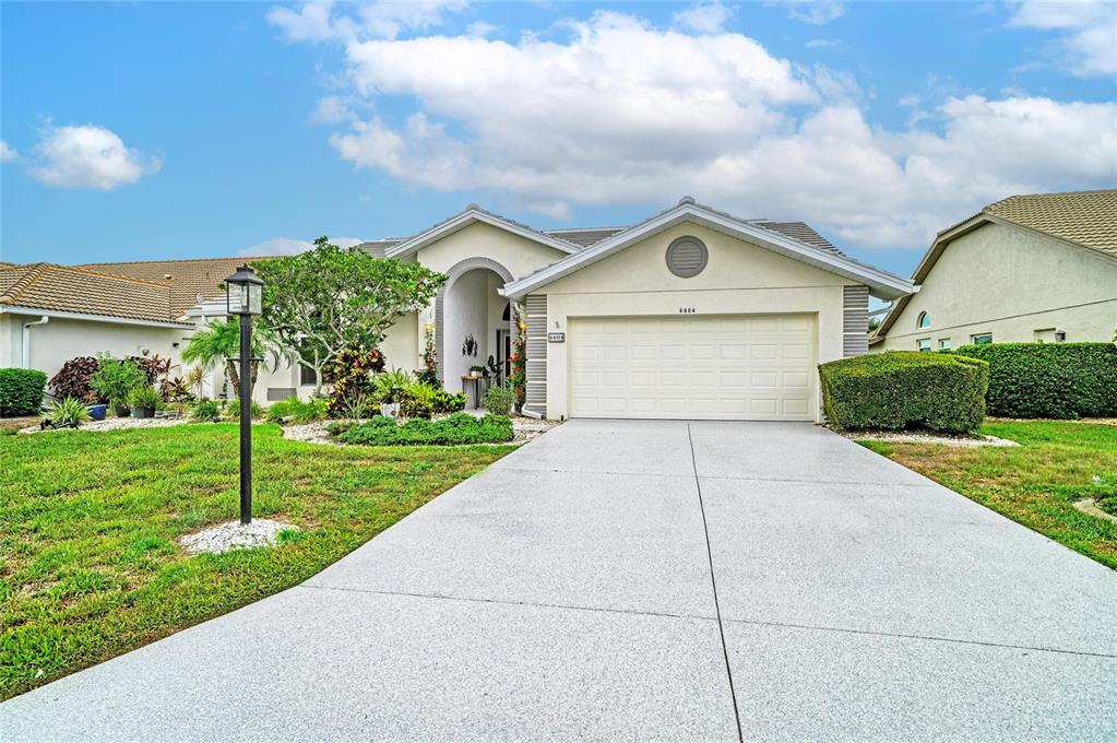 A single-story house with a beige stucco exterior, a two-car garage, and a concrete driveway — 6604 STONE RIVER ROAD, BRADENTON, FL