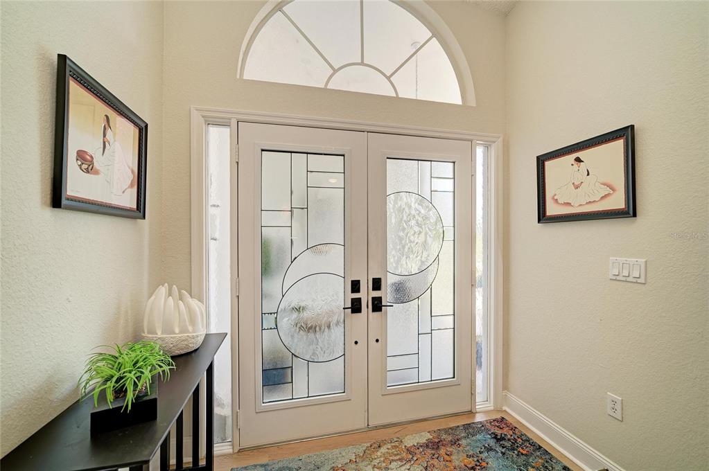 An entryway features double glass-paneled doors, a semi-circular transom window, and two framed wall pictures — 6604 STONE RIVER ROAD, BRADENTON, FL