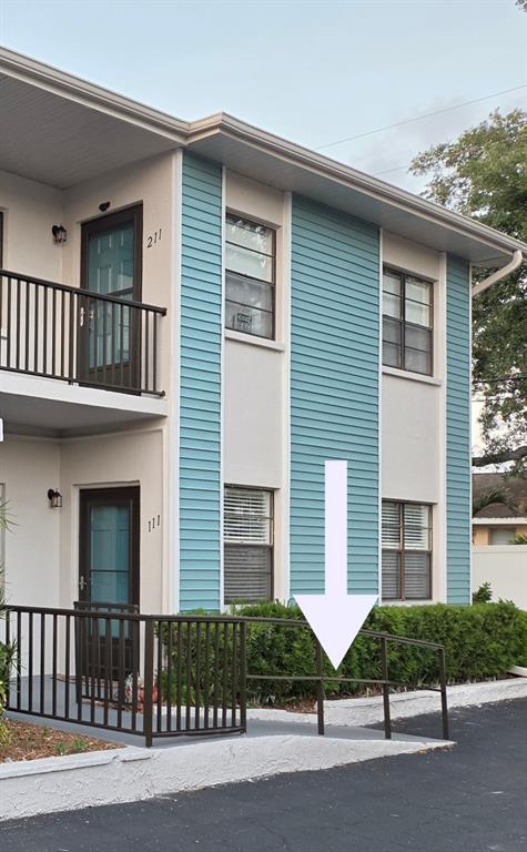 An exterior view of a two-story apartment building featuring a wheelchair ramp with metal railings — 5925 TERRACE PARK DRIVE N UNIT 111, ST PETERSBURG, FL