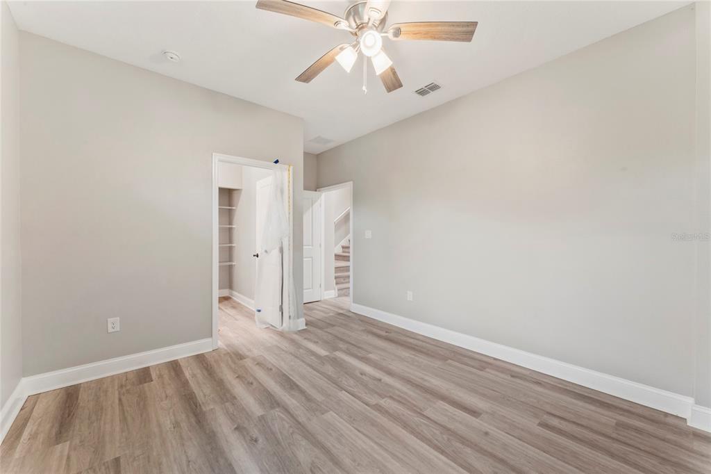 An empty bedroom features light gray walls, wood-look flooring, a ceiling fan, and two doorways — 809 W LINEBAUGH AVE UNIT 2A, TAMPA, FL