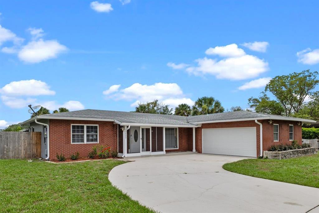 A single-story brick house features a white garage door and a concrete driveway — 2622 HIBISCUS COURT, DELTONA, FL