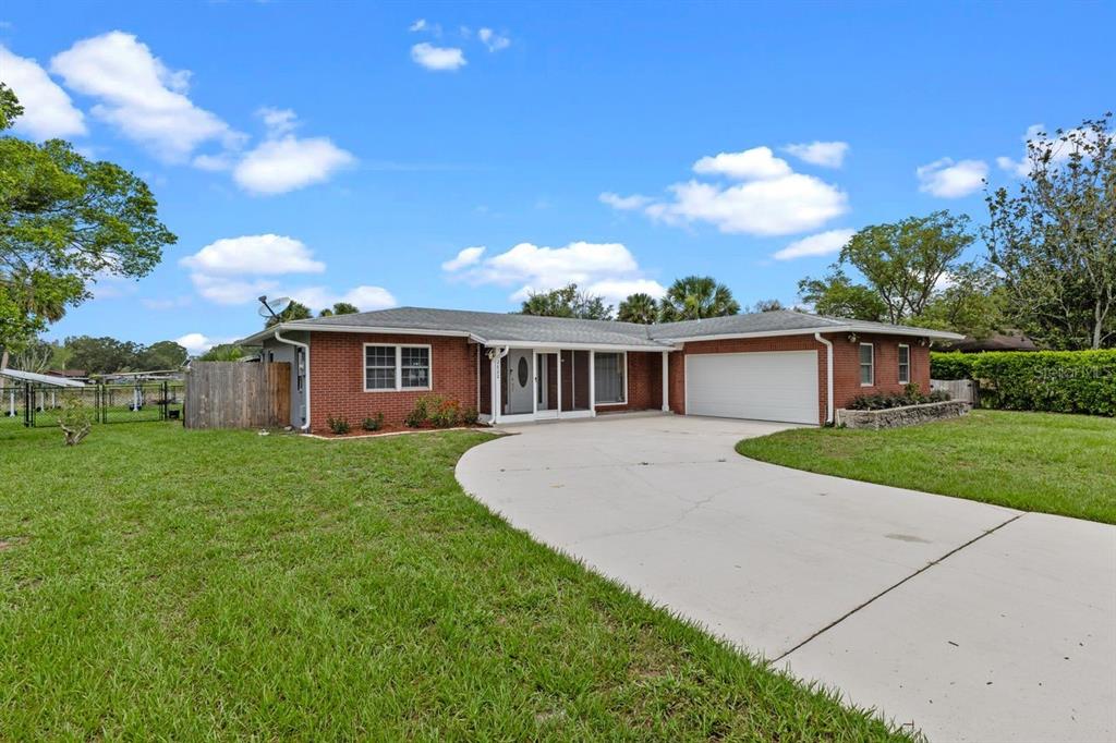A single-story brick house with a white garage door and a curved concrete driveway — 2622 HIBISCUS COURT, DELTONA, FL