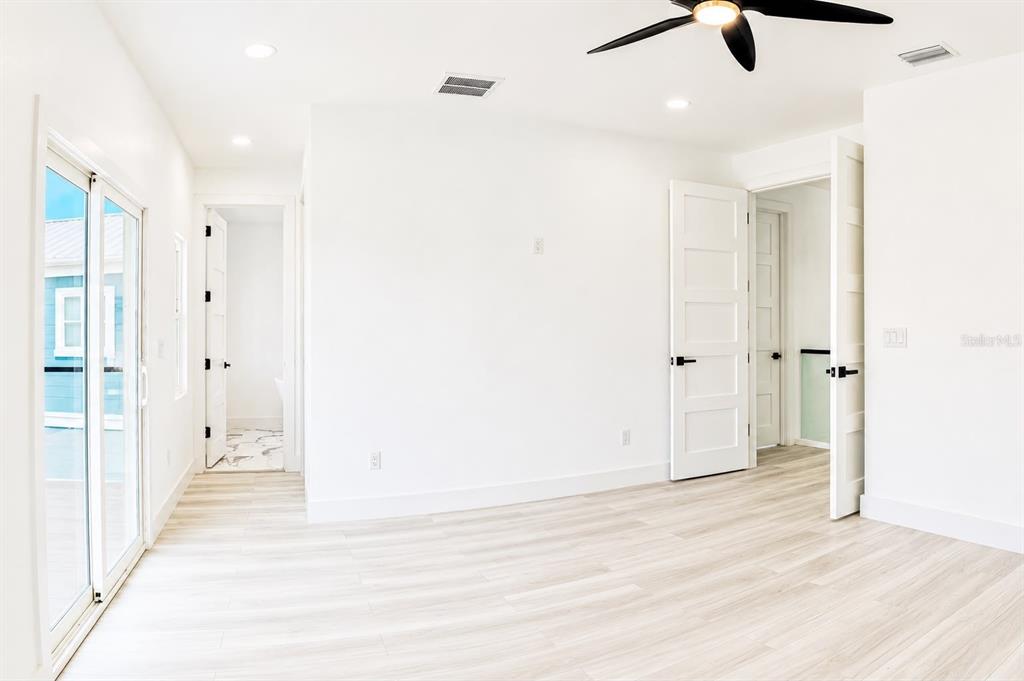 A modern kitchen with white cabinets, black countertops, and marble-look tile flooring opens to outdoors — 6510 SIMONE SHORES CIR, APOLLO BEACH, FL