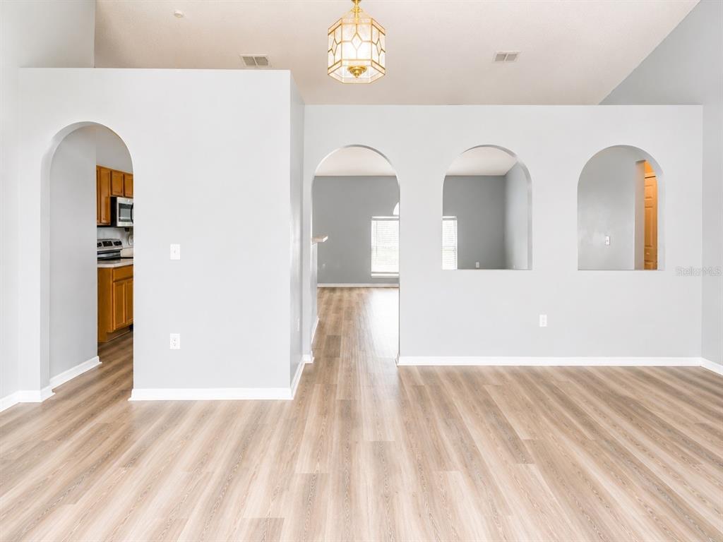 An open-concept living area features wood-look flooring, a kitchen pass-through, and sliding glass doors — 3080 UTAH DRIVE, DELTONA, FL