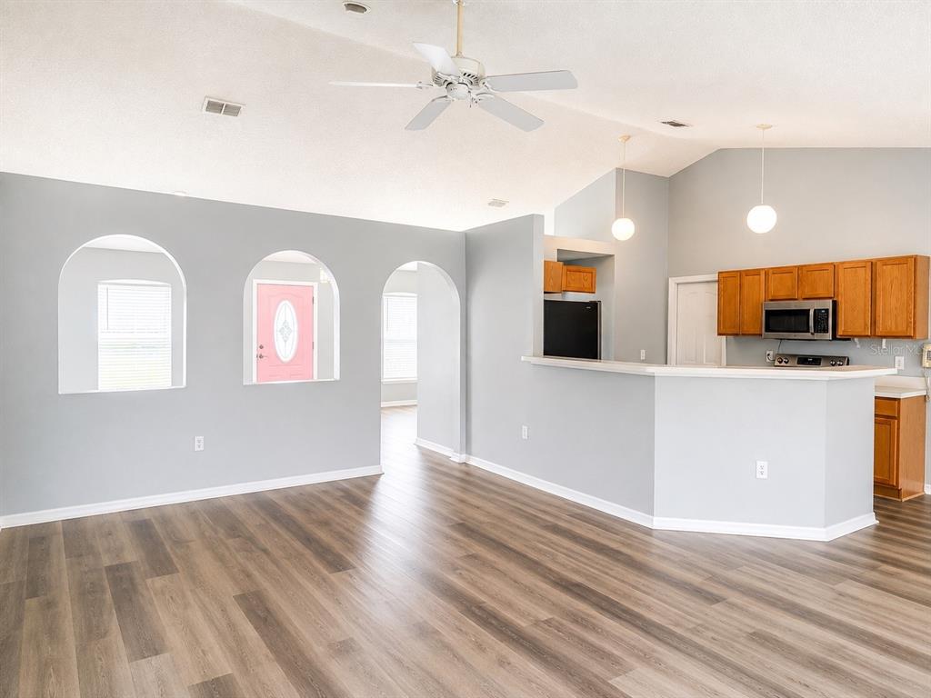 An empty room features gray walls, arched cutouts, and wood-look vinyl plank flooring — 3080 UTAH DRIVE, DELTONA, FL