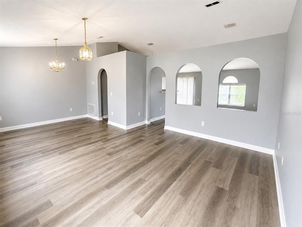 An empty room features gray walls, wood-look flooring, and two distinct hanging light fixtures — 3080 UTAH DRIVE, DELTONA, FL