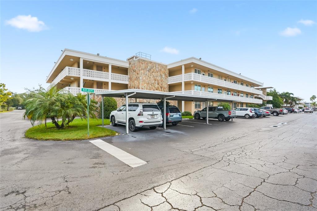 A three-story apartment building with a stone facade and a covered parking area at sunset — 5095 BAY STREET NE UNIT 210, ST PETERSBURG, FL