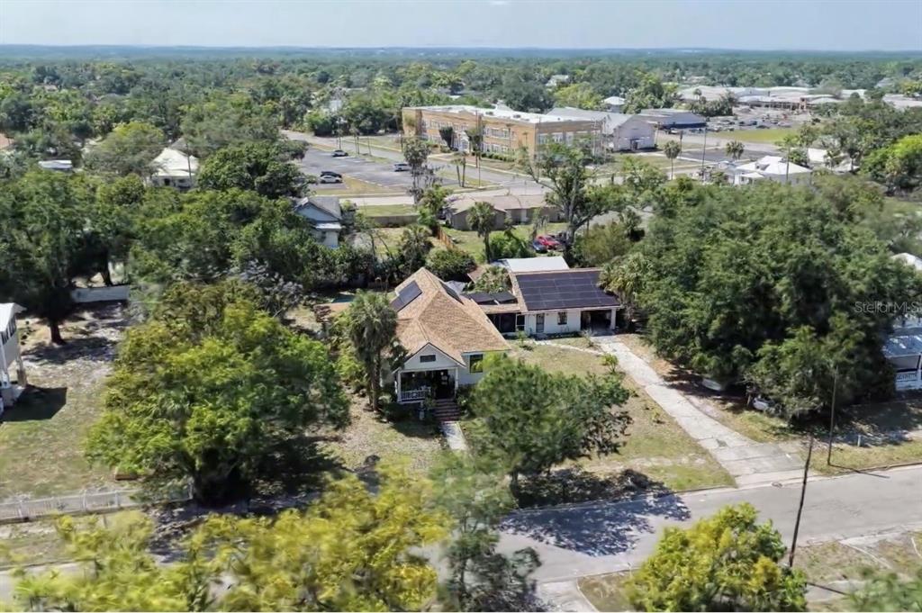An aerial view shows a house with solar panels on its roof surrounded by trees — 223 N MONROE AVENUE, ARCADIA, FL