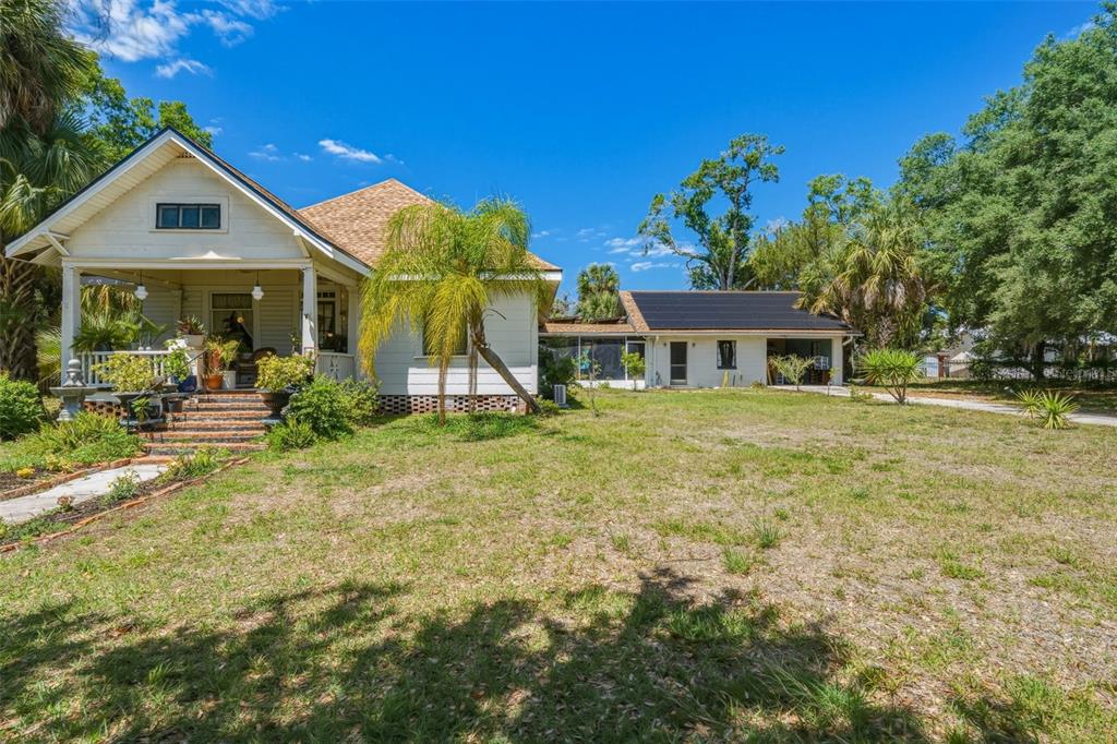 A white house with a front porch and a detached garage with solar panels — 223 N MONROE AVENUE, ARCADIA, FL