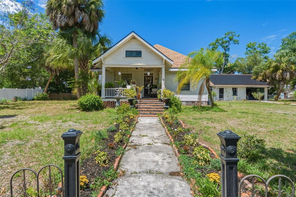 A single-story house with a front porch, walkway, and palm trees under a blue sky — 223 N MONROE AVENUE, ARCADIA, FL