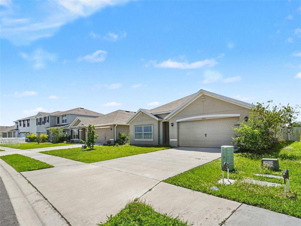 A single-story suburban house with a beige exterior, a two-car garage, and a concrete driveway — 12151 KINGSLEY TRAIL, PARRISH, FL