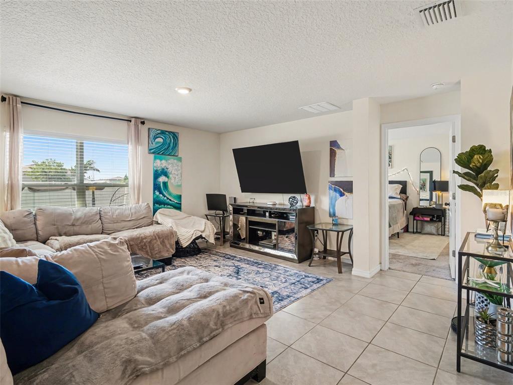 A living room features a sectional sofa, a wall-mounted television, and tile flooring — 12151 KINGSLEY TRAIL, PARRISH, FL