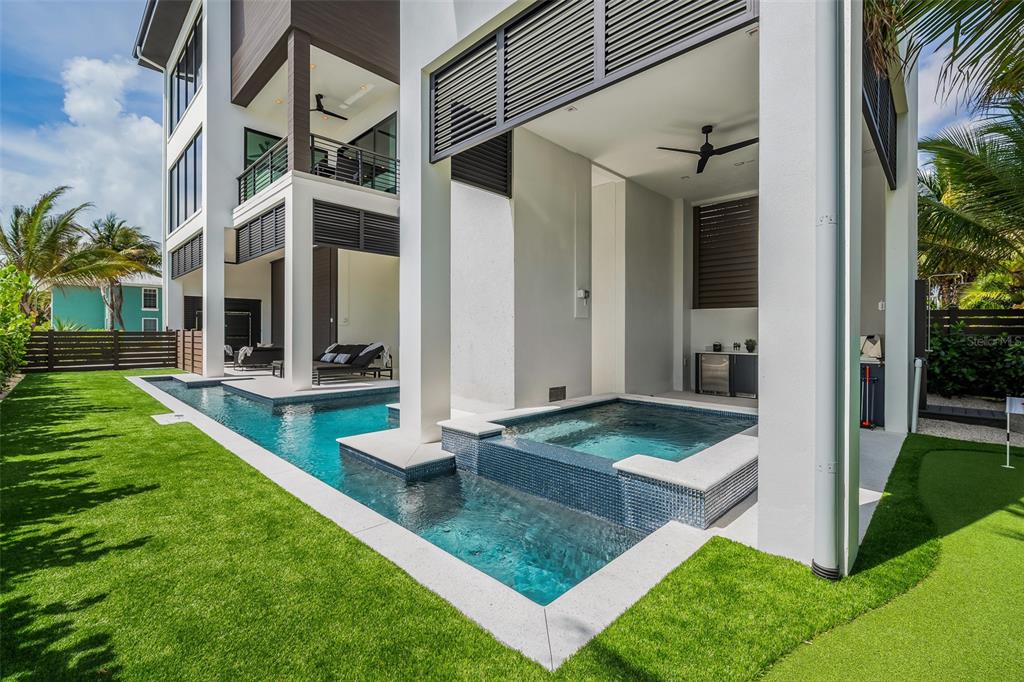 A modern home features a covered patio with a built-in spa and a lap pool — 101 7TH STREET S, BRADENTON BEACH, FL