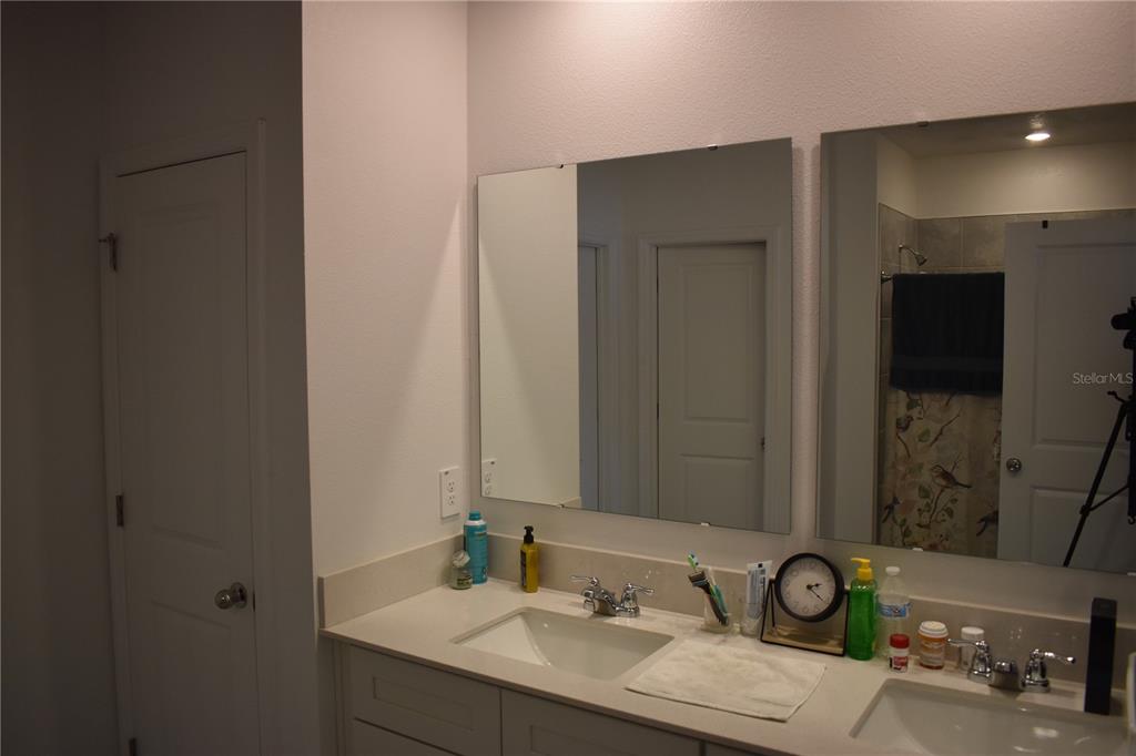 A bathroom vanity with two sinks, two frameless mirrors, and light-colored countertops — 1406 DEEPWATER CIRCLE, EAGLE LAKE, FL