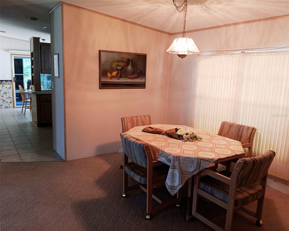 A dining area features a table with four chairs, a hanging lamp, and wall art — 2103 STACEY DRIVE, MOUNT DORA, FL