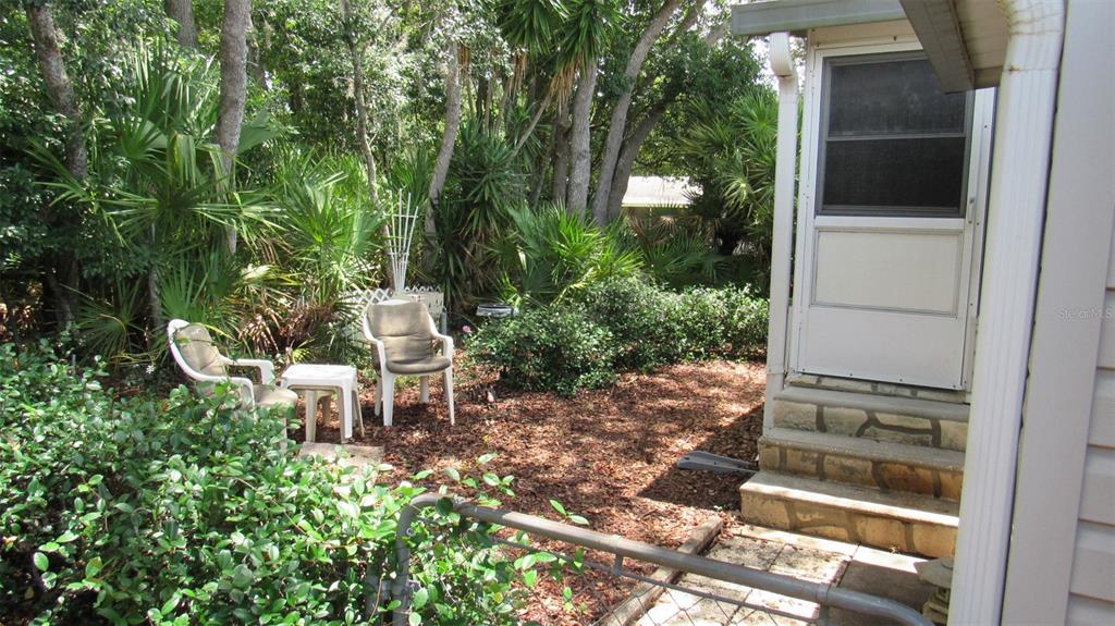 A small patio with two chairs and a table sits beside a house entrance — 2103 STACEY DRIVE, MOUNT DORA, FL