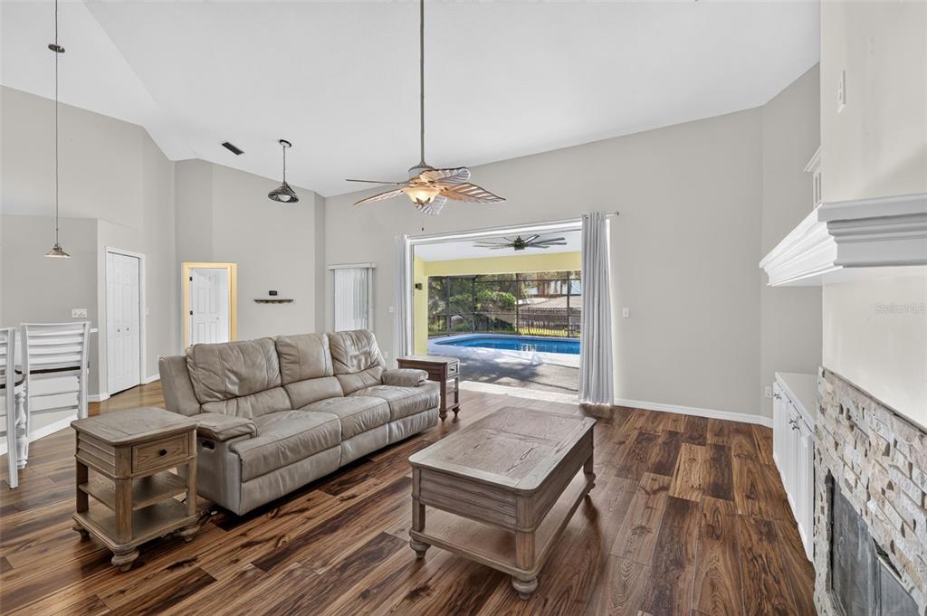 A living room with wood floors, a leather sofa, and a sliding door to a pool — 35546 CEDAR LANE, LEESBURG, FL