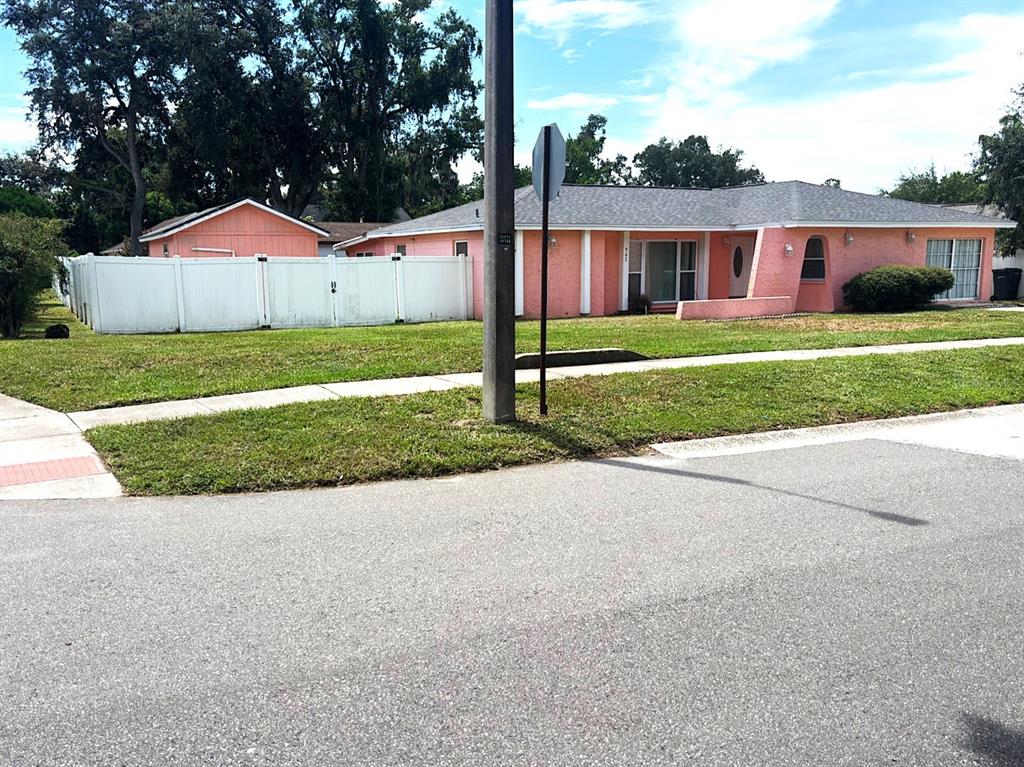 A single-story pink house with a gray roof and a white fence sits on grass — 902 SAMY DRIVE, TAMPA, FL