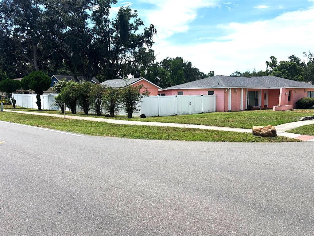 A pink, single-story house with a gray roof sits behind a white vinyl fence — 902 SAMY DRIVE, TAMPA, FL