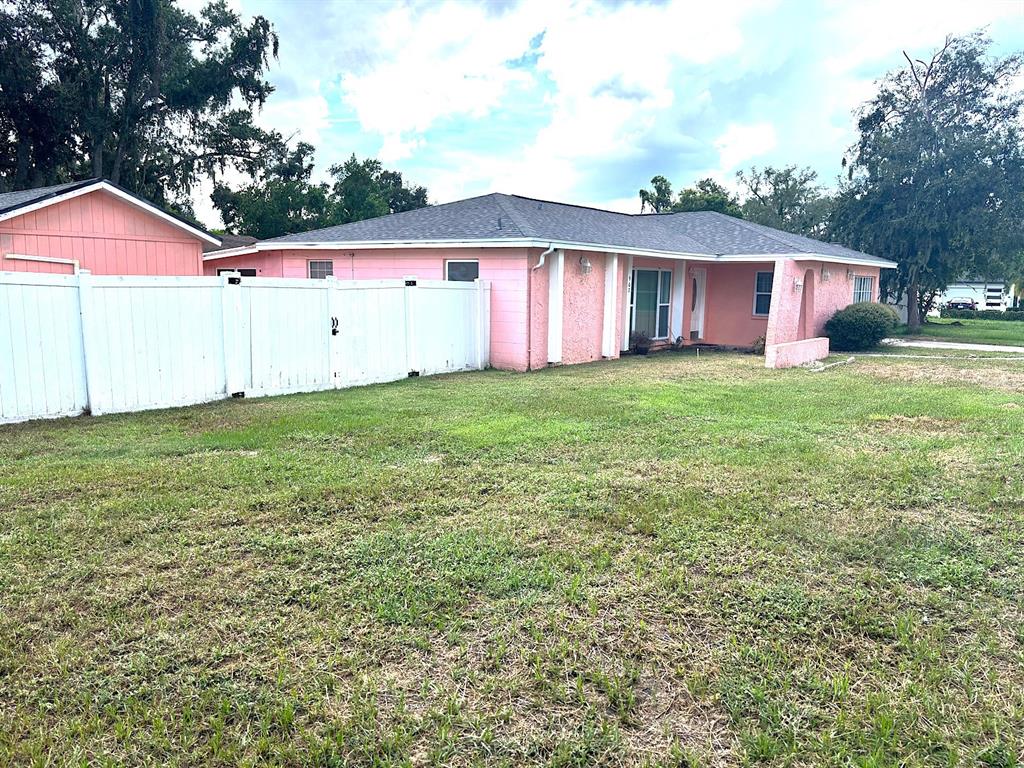 A pink, single-story house with a white vinyl fence sits on a corner lot — 902 SAMY DRIVE, TAMPA, FL
