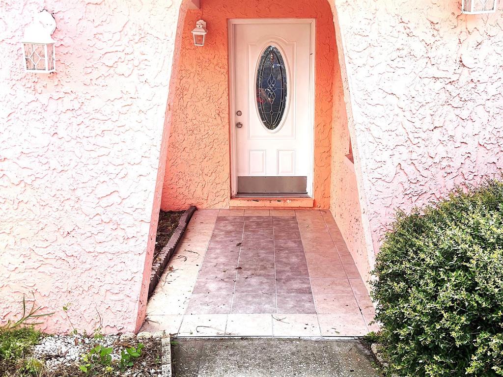 A pink, single-story house with a white fence stands on a grassy lot — 902 SAMY DRIVE, TAMPA, FL