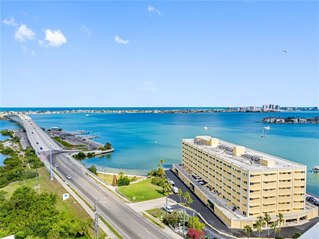 An aerial view shows a swimming pool between two apartment buildings near a bay — 100 BLUFF VIEW DRIVE UNIT 404C, BELLEAIR BLUFFS, FL
