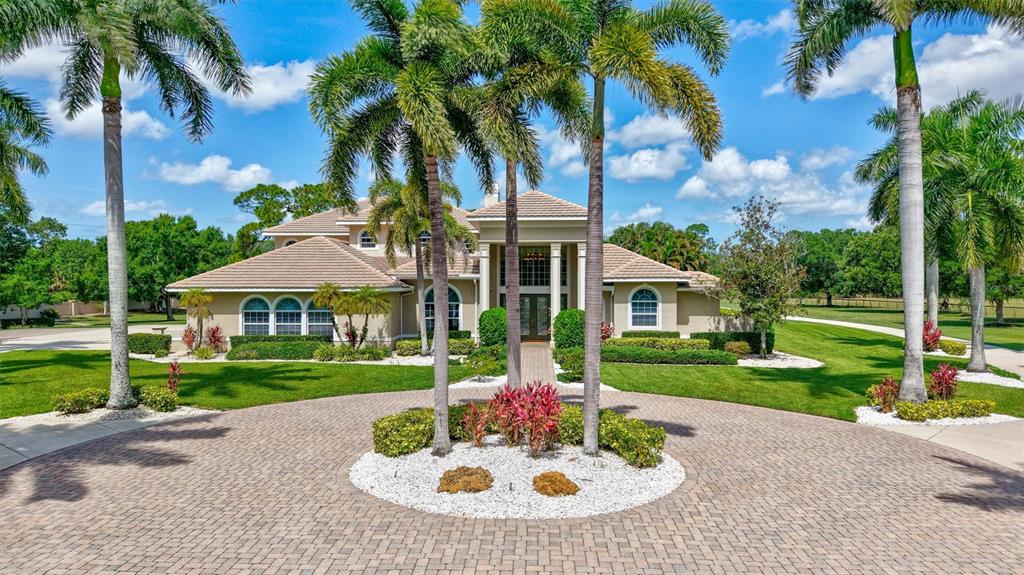 A large two-story house with a tiled roof is surrounded by palm trees and lawns — 1045 FOX CREEK DRIVE, SARASOTA, FL