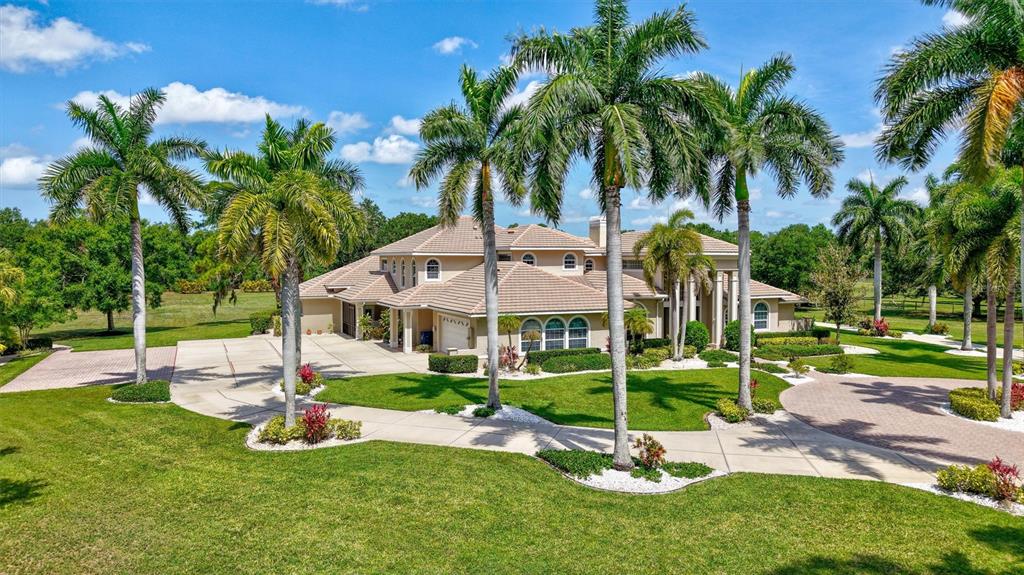 A large two-story house with a paved circular driveway and palm trees in the front yard — 1045 FOX CREEK DRIVE, SARASOTA, FL