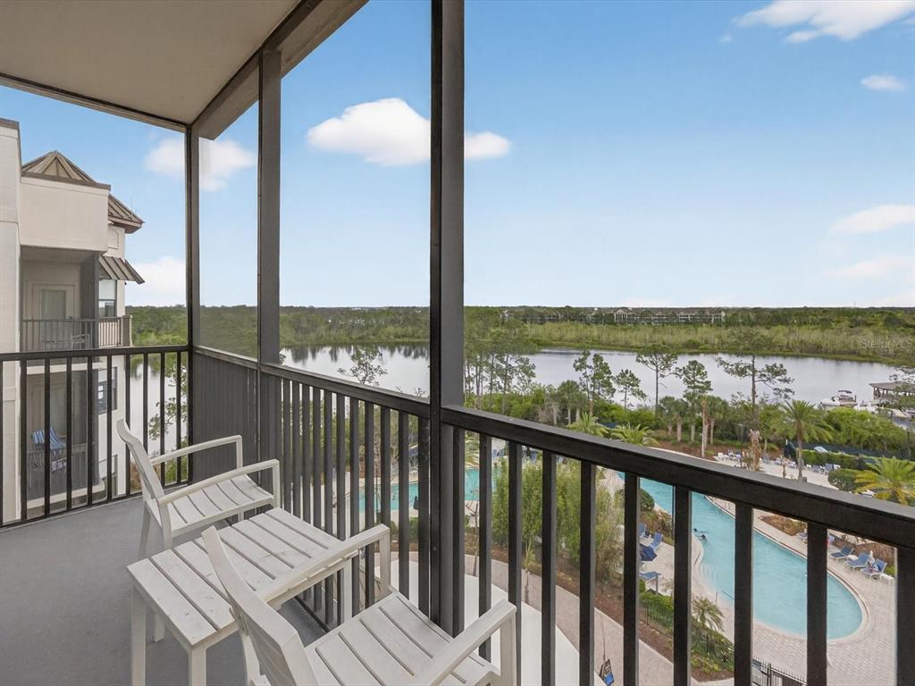 A screened balcony overlooks a swimming pool and a lake surrounded by trees — 14501 GROVE RESORT AVENUE UNIT 1721, WINTER GARDEN, FL