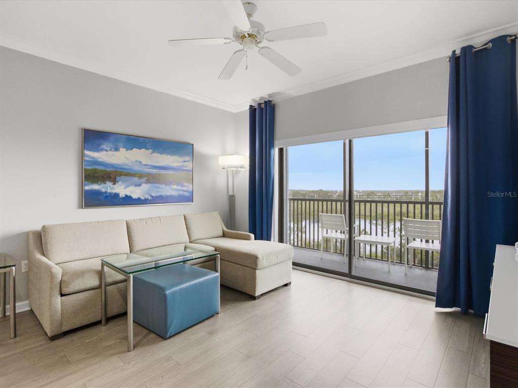 A living room features a beige sectional sofa, glass coffee table, and a balcony view — 14501 GROVE RESORT AVENUE UNIT 1721, WINTER GARDEN, FL
