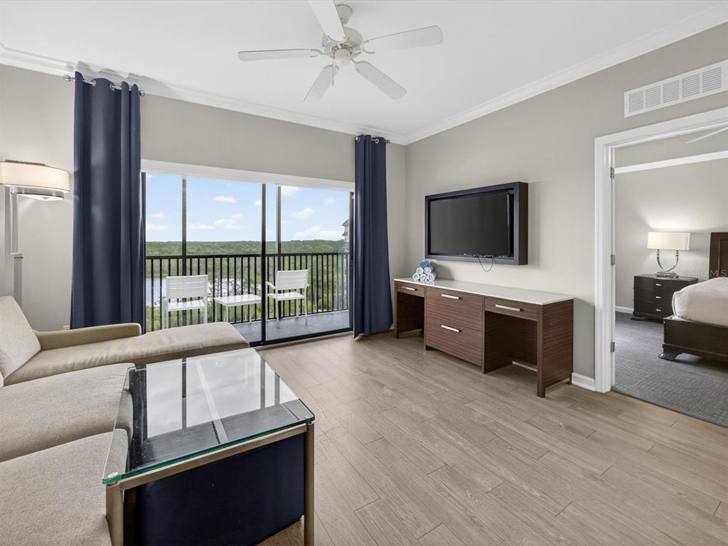 A living room features a glass-topped coffee table, a wall-mounted television, and a balcony view — 14501 GROVE RESORT AVENUE UNIT 1721, WINTER GARDEN, FL