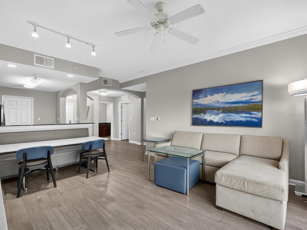 A living room features a sectional sofa, a breakfast bar with chairs, and wood flooring — 14501 GROVE RESORT AVENUE UNIT 1721, WINTER GARDEN, FL