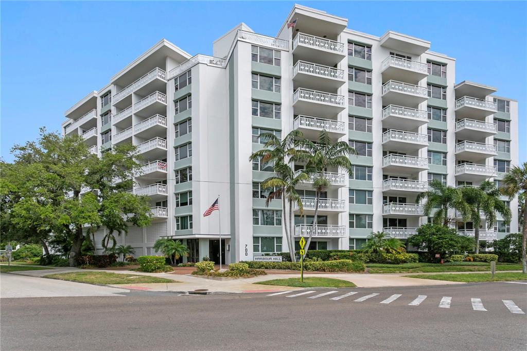 A multi-story white apartment building with balconies and palm trees stands near a street corner — 700 BEACH DRIVE NE UNIT 603, ST PETERSBURG, FL