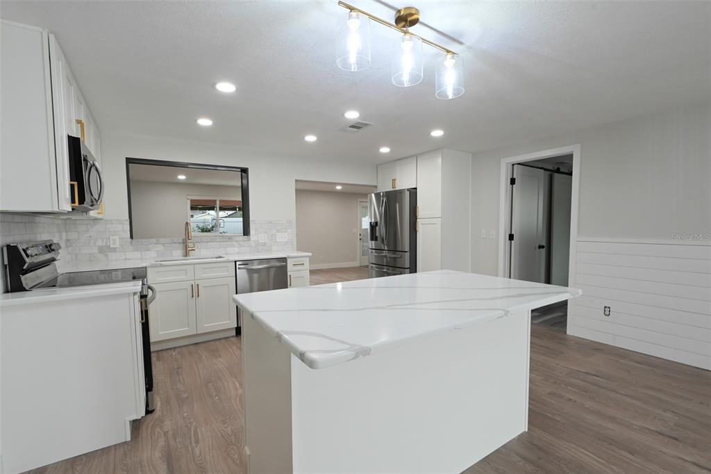 A modern entryway features a glass console table, a rectangular mirror, a lamp, and a plant — 11987 106TH AVENUE, SEMINOLE, FL