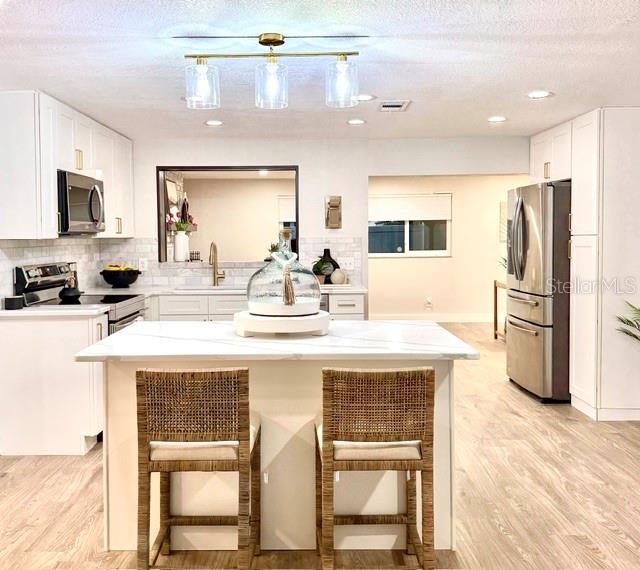 A bright, open-concept kitchen and living area featuring white cabinetry, a marble-topped island, and shiplap — 11987 106TH AVENUE, SEMINOLE, FL