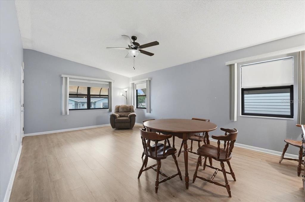 A dining area with a round wooden table and chairs sits in a light-walled room — 3231 BEAR CREEK LANE, LAKELAND, FL